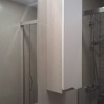 Esto es un baño, los muebles combinando blanco mate y madera en tono beige con tirador uñero